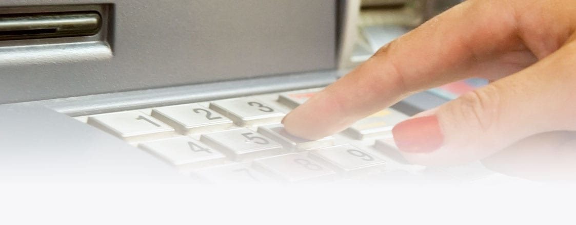 Customer entering a PIN at an ATM keypad